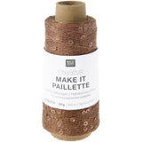 A spool of brown decorative twine with sequins, wrapped in a white paper band labeled 'RICO DESIGN creative MAKE IT PAILLETTE'.