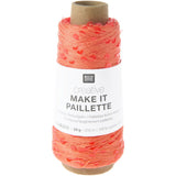 A spool of Rico Design Creative Make It Paillelette yarn in a vibrant coral-orange color, wound on a brown cardboard core with a white paper label.