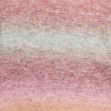A close-up of a knitted fabric with a soft gradient pattern blending dusty pink, muted sage green, and light peach tones.