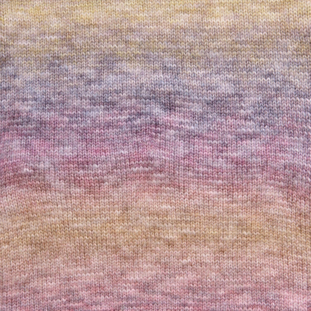 A close-up of a knitted fabric with a soft gradient pattern blending pastel yellow, lavender, pink, and peach tones.