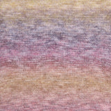 A close-up of a knitted fabric with a soft gradient pattern blending pastel yellow, lavender, pink, and peach tones.