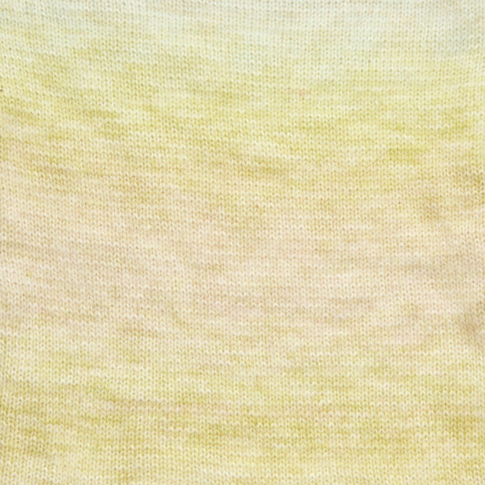 A close-up of a fine knit fabric with a soft gradient transitioning from pale yellow at the top to a warm cream/beige at the bottom.