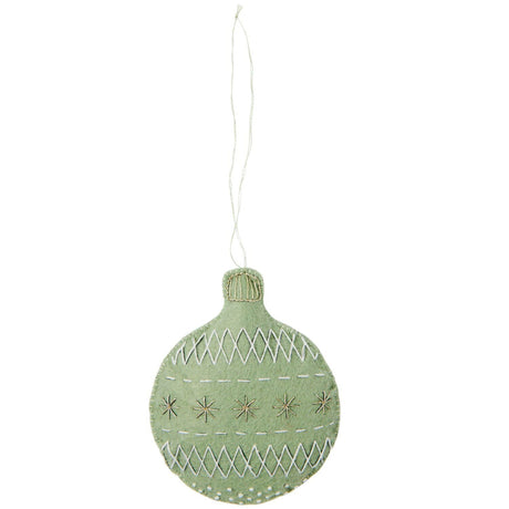 A light sage green felt Christmas ornament shaped like a bauble, featuring white embroidered geometric patterns and star details, hanging from a thin white string against a plain white background.