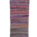 A close-up of a textured, fuzzy striped fabric or scarf with horizontal bands of purple, pink, orange, and brown on a white background.