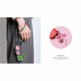 Keychain with pink cat charm and colorful beads held by a person, with a close-up inset on a white background.