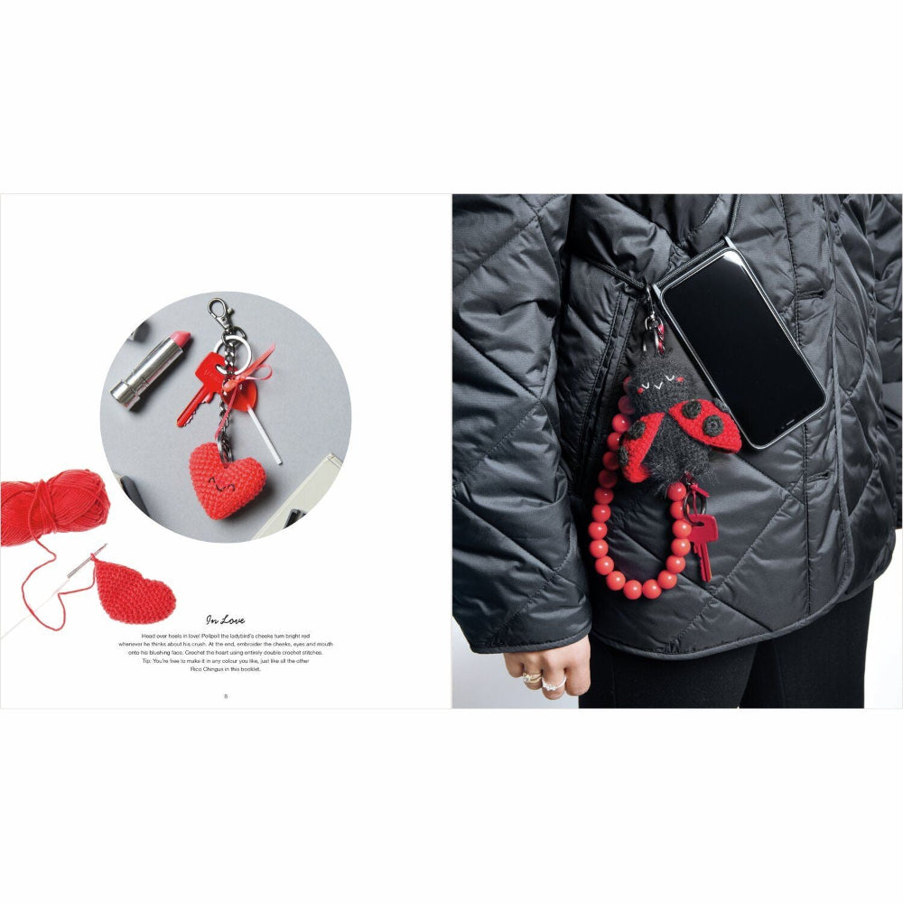 Red heart-shaped keychain and charm on a gray surface with a person wearing a black jacket with a red charm.