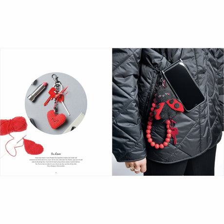 Red heart-shaped keychain and charm on a gray surface with a person wearing a black jacket with a red charm.