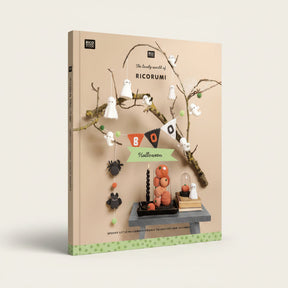 A styled product photo for a crochet and decor kit titled 'The lovely world of RICORUMI' featuring Halloween-themed crocheted ghost figures, a black spider, orange pumpkin decorations, a black candle, and a small table setup against a beige background with decorative branches.