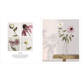 An open book or magazine spread showing floral photography and a small inset collage of flowers. The right page features a clear glass vase with white daisies and pink coneflowers on a wooden surface against a soft light background with flower shadows.