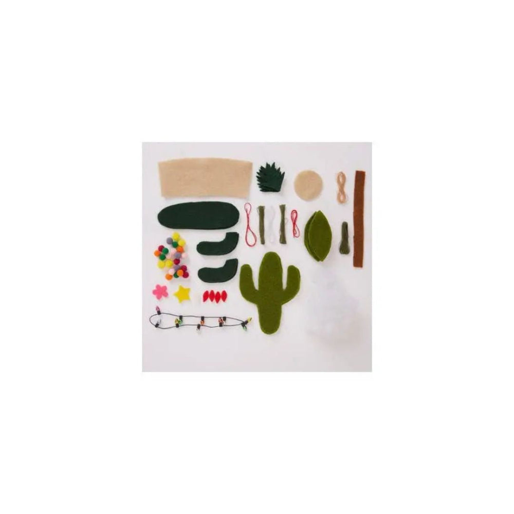 A felt craft kit with various desert-themed shapes including a cactus, leaves, bark, and small colourful felt accents, arranged on a white background.