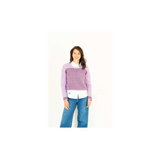 A woman modeling a purple and white patterned crochet sweater over a white collared shirt and blue jeans, set against a plain white background.