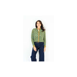 A woman modeling a green and yellow geometric patterned crochet cardigan with dark blue jeans against a plain white background.