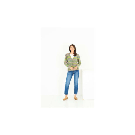 A woman modeling a green and yellow striped knit sweater with blue jeans and tan shoes, standing against a plain white studio background.