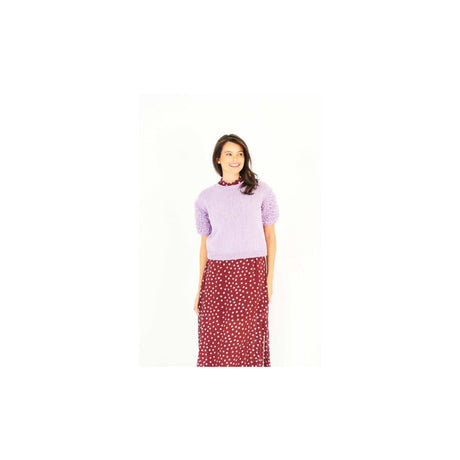 A woman modeling a short-sleeve lavender knit top with textured puff sleeves and a red skirt with a white polka dot pattern, set against a plain white background.