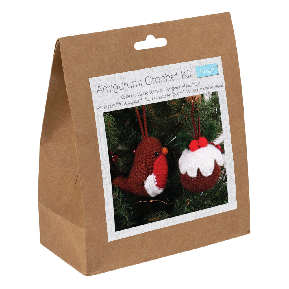 A brown kraft paper bag package labeled 'Amigurumi Crochet Kit' with a photo of crocheted Christmas ornaments on the front, photographed on a white background.