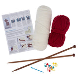 Knitting kit with two balls of yarn (one cream, one red), wooden knitting needles, a blue needle, colourful stitch markers, and an instruction booklet on a white background.