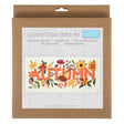 A Counted Cross Stitch Kit by trimte in its original brown kraft paper packaging, featuring a sample of the 'AUTUMN' cross-stitch design with orange letters and colourful autumn leaves.