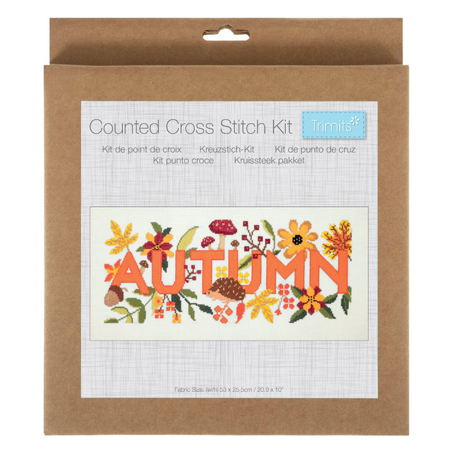 A Counted Cross Stitch Kit by trimte in its original brown kraft paper packaging, featuring a sample of the 'AUTUMN' cross-stitch design with orange letters and colourful autumn leaves.