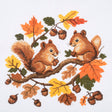 A cross-stitch style illustration of two brown squirrels sitting on a tree branch with orange, yellow, and green autumn leaves and acorns on a white background.