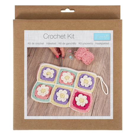 Crochet kit packaging with a sample of crocheted squares on a wooden surface.
