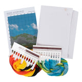 A needlework kit laid out on a white background, including a printed canvas design sheet, two large white mesh canvases, two skeins of embroidery floss in warm orange/yellow/black and cool blue/green tones, and two color reference cards.