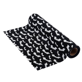Black and white patterned fabric with a repeating bat silhouette design, shown partially rolled on a white background.
