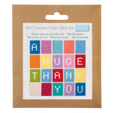 A Mini Counted Cross Stitch Kit by mini kit, featuring a colorful 'HUGE THANK YOU' cross stitch design on a white grid card, mounted on a brown kraft paper backing card with a hanging tab.