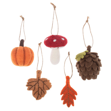 Five autumn-themed felt ornaments hanging from twine strings on a white background: a pumpkin, a red-and-white mushroom, a pinecone, a tan leaf, and an orange leaf.