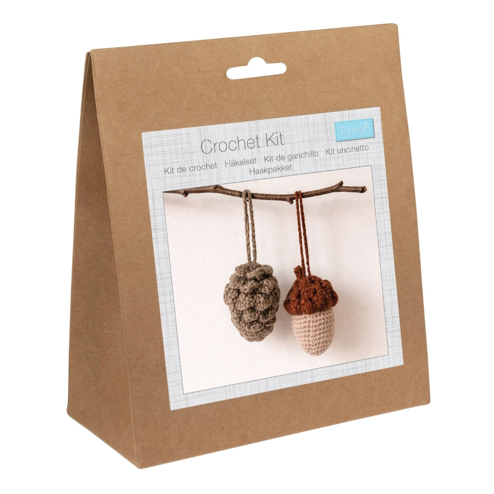 A brown kraft paper bag package for a crochet kit, featuring a front label with a photo of two crocheted acorns hanging from a twig.