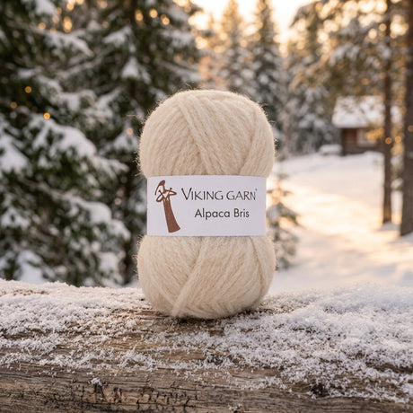 A single ball of fluffy Alpaca Bris yarn by Viking Garn in a light cream colour, with a white paper label wrapped around the centre.