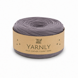 A roll of Yarnly faux leather t-shirt yarn in a muted grayish purple color, wrapped in a kraft paper band with the brand name 'YARNLY' printed on it, set against a plain white background.