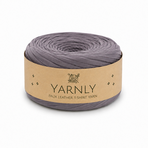 A roll of Yarnly faux leather t-shirt yarn in a muted grayish purple color, wrapped in a kraft paper band with the brand name 'YARNLY' printed on it, set against a plain white background.