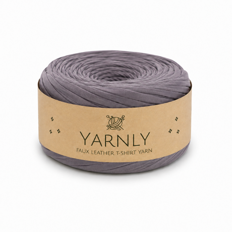 A roll of Yarnly faux leather t-shirt yarn in a muted grayish purple color, wrapped in a kraft paper band with the brand name 'YARNLY' printed on it, set against a plain white background.