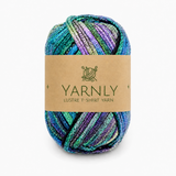 A skein of Yarnly Lustre T-Shirt Yarn with a brown paper label, featuring variegated colors of teal, green, purple, and blue with a shimmering finish, set against a plain white background.